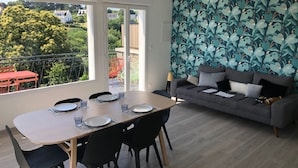 Ein modernes Wohnzimmer mit Essbereich, einem grauen Sofa und einer Wand mit Muster.