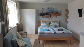 Ein Schlafzimmer mit Bett, Sofa, Sessel, Kleiderschrank und einem Gemälde an der Wand.