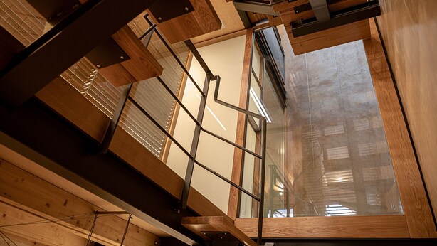 Un interno moderno con travi a vista in legno, un soffitto in vetro e vista sulla città.