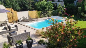 A backyard with a swimming pool, outdoor furniture, and potted plants.