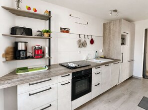 A modern kitchen with white cabinetry, a built-in oven, and a coffee maker on the countertop.