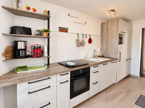 A modern kitchen with a built-in oven, a coffee maker, and a kettle on the counter. - Apartment near port center and beach - Sea view (Courseulles-sur-Mer)