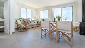 Een moderne woonkamer met een bank, een eettafel met stoelen en een keukenhoek.
