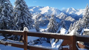 Un paysage de montagne enneigé, avec une clôture en bois au premier plan.