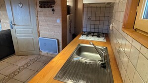 Une cuisine avec des meubles en bois, un évier en acier inoxydable et un dosseret carrelé.