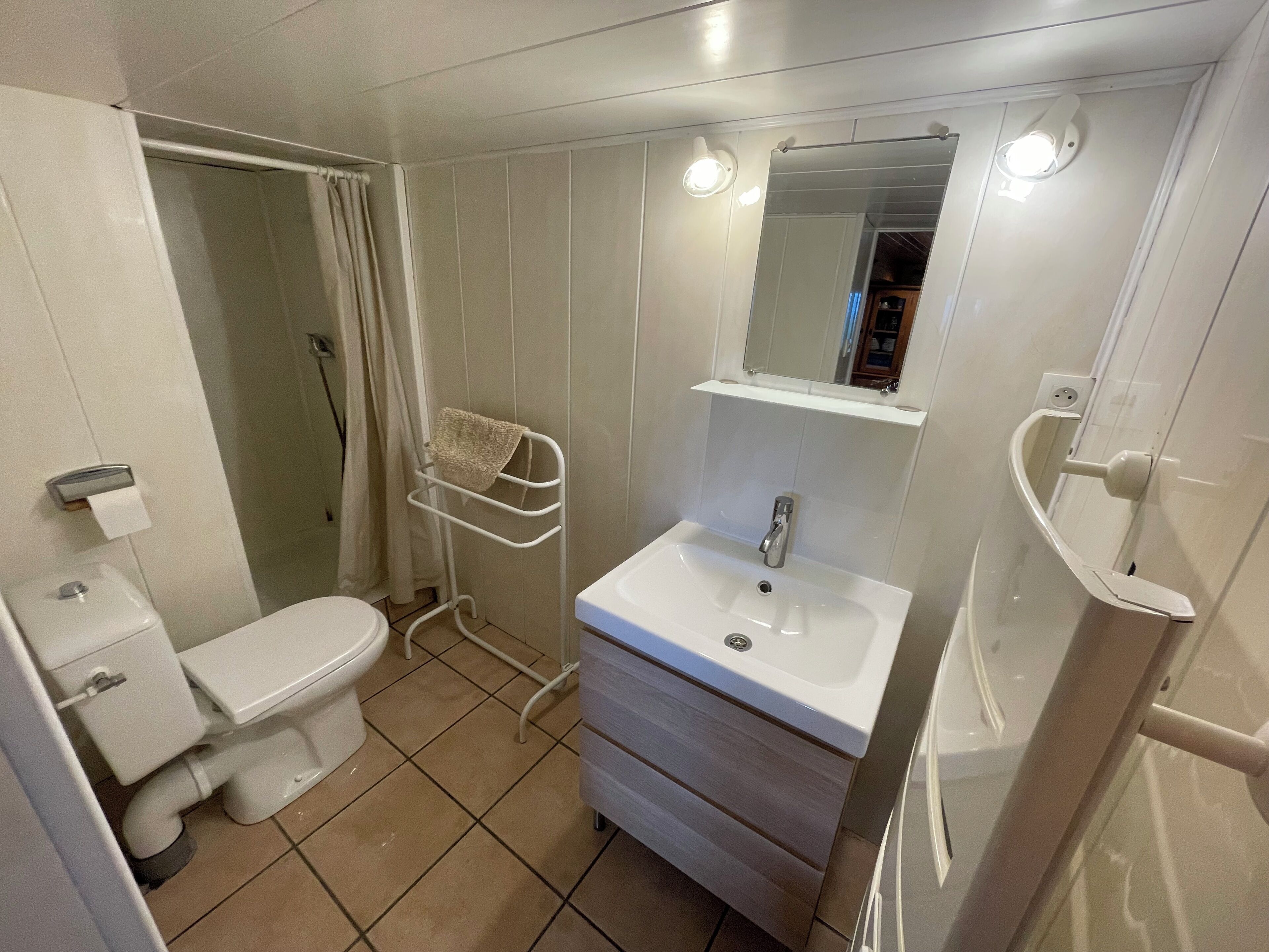 Un baño pequeño y limpio con inodoro, lavamanos y zona de ducha.