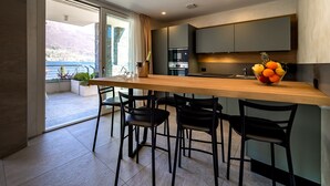 A modern kitchen with a wooden countertop, four black chairs, and a fruit bowl.