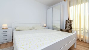 Ein ordentlich eingerichtetes Schlafzimmer mit Bett, Nachttisch, Stuhl und einem großen Spiegel.
