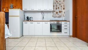 Eine Küche mit weißen Schränken, einem Kühlschrank, einer Kaffeemaschine und einem Backofen.