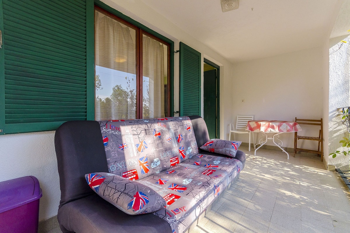 Un canapé recouvert d’un tissu à motifs, une petite table avec une nappe à carreaux et une chaise.