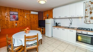 Eine kleine Küche mit weißen Schränken, einem Herd und einem Kühlschrank.