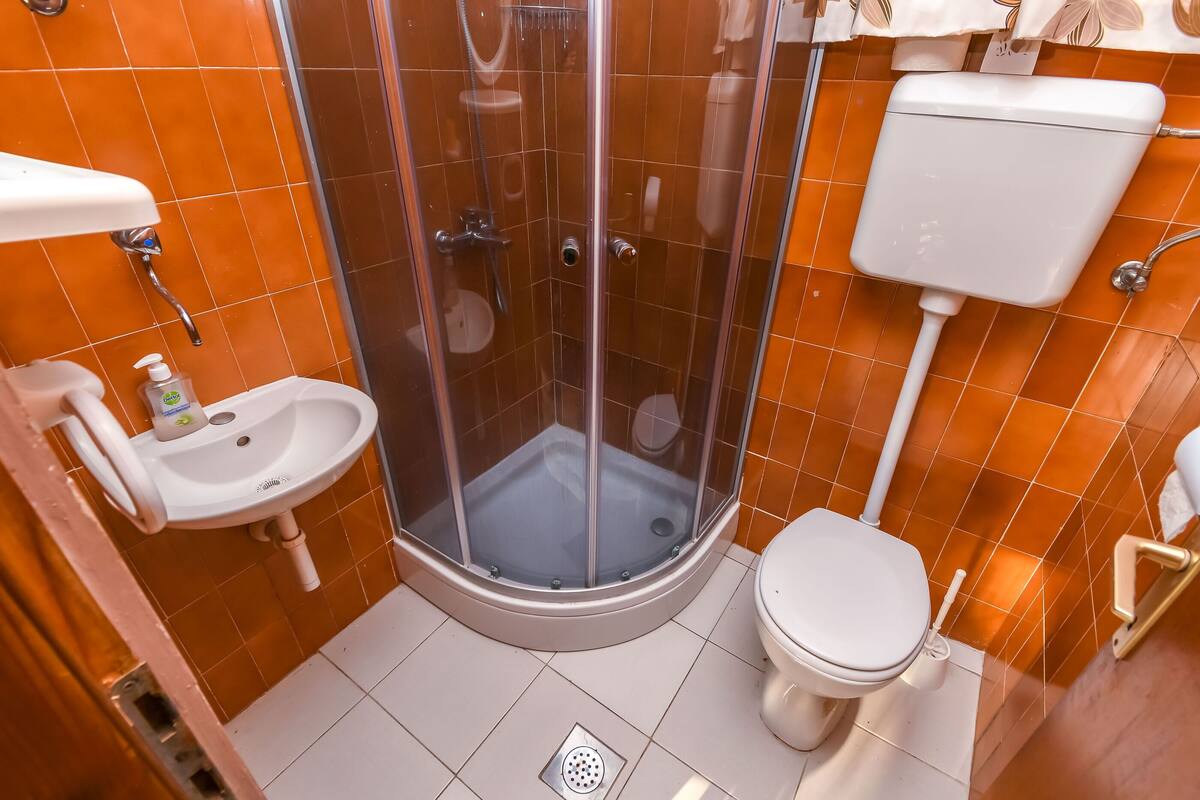 Une salle de bain avec une douche à parois de verre, des toilettes et un lavabo.