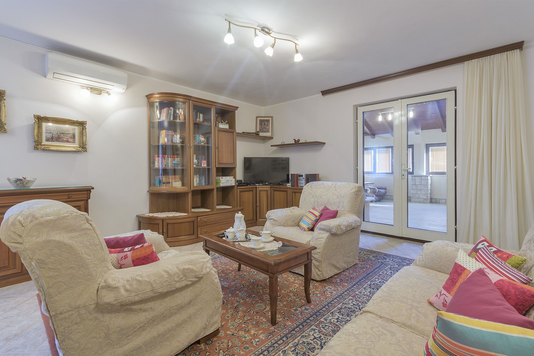 Una sala de estar con sofá, sillones, una mesa de centro, un aparador y televisor.