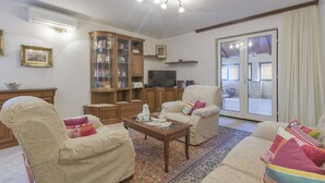 Un salon comprenant un canapé, des fauteuils, une table basse, un meuble et un téléviseur.