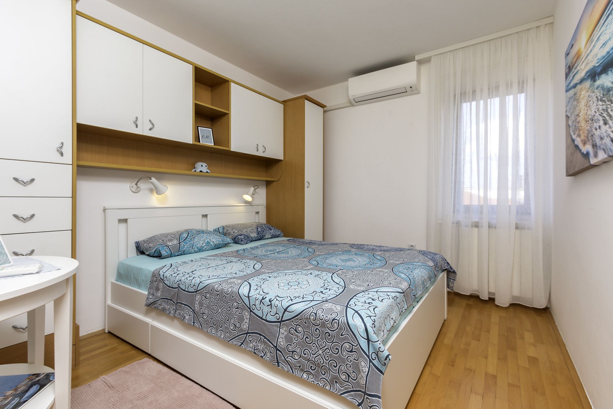 A bedroom with a bed, bedside tables, a desk, and a window with curtains.