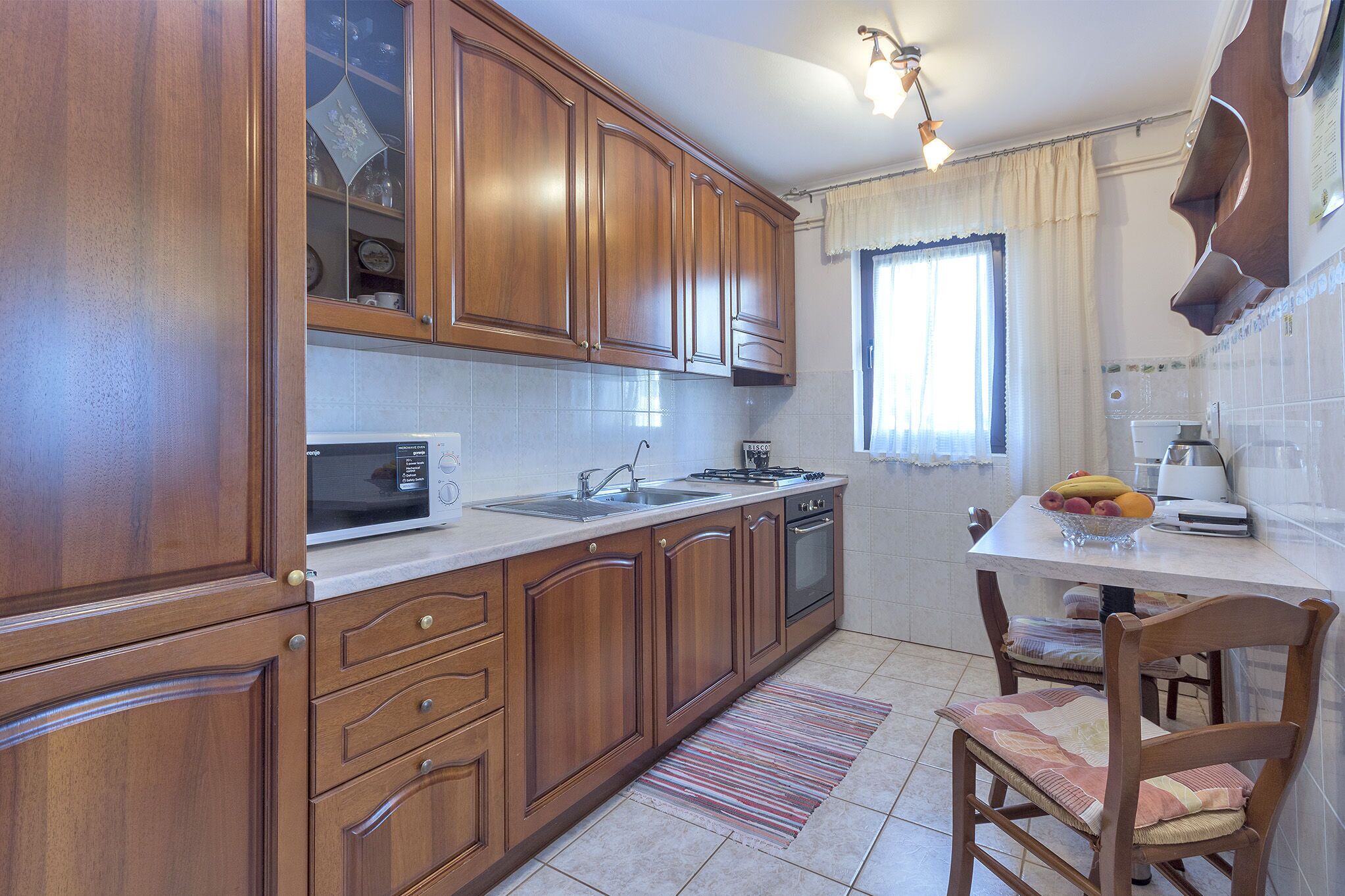 A kitchen with wooden cabinets, a microwave, a sink, and a dining table with chairs.