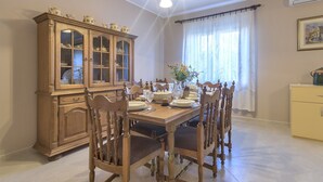 Une salle à manger avec un buffet en bois, une table à manger dressée pour quatre personnes et une fenêtre avec des rideaux.