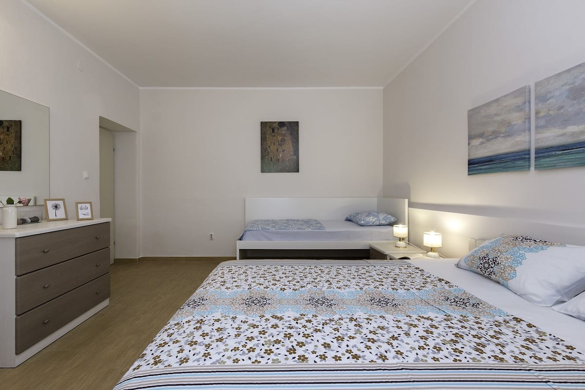 Ein Schlafzimmer mit einem Bett, Nachttischen, einer Kommode und Bildern an den Wänden.