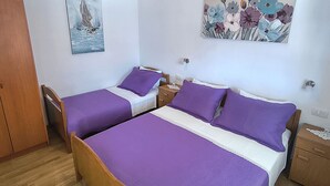 A room with two beds, a wooden wardrobe, a nightstand, and two wall-mounted paintings. - Apartments Matas (Rogoznica)
