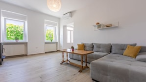 Una sala moderna con un sofá seccional gris, una mesa de centro de madera y una lámpara colgante.