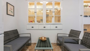Ein Zimmer mit zwei grauen Sofas, einem kleinen Tisch mit Schale und Kerze sowie einem Schrank mit Glaswaren.