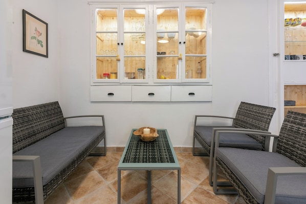 A room with two grey sofas, a small table with a bowl and candle, and a cabinet with glassware. - House Goldie (Tribalj)