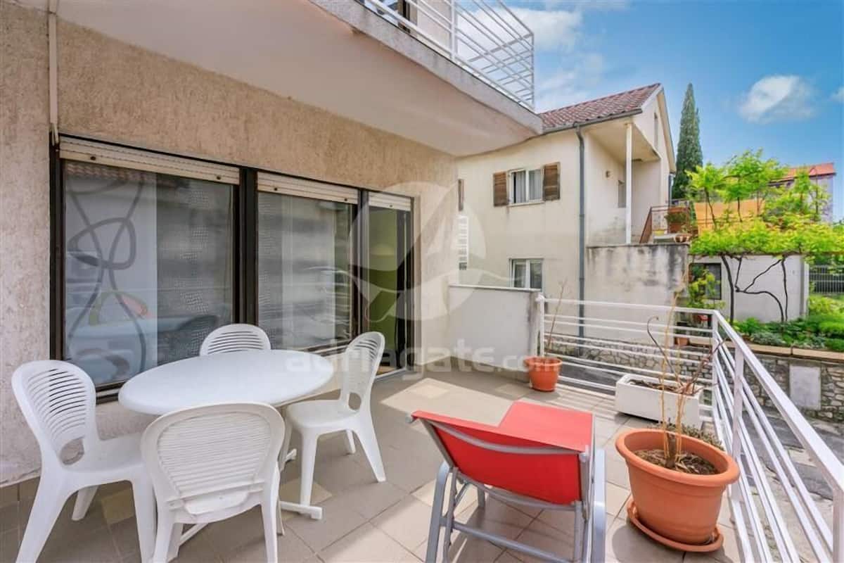 A balcony with a table and chairs, a potted plant, and a railing.