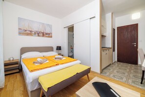 A bedroom with a bed, a bedside table, a chair, a desk, and a painting on the wall. - Apartments Zec (Selce)
