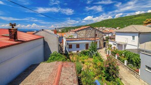 Zona residencial con edificios de piedra y techos de tejas, cielo despejado y abundante vegetación.