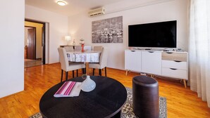 Una sala de estar moderna con comedor, televisor de pantalla plana y un cuadro en la pared.