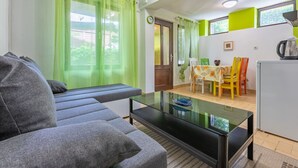 Una sala de estar con un sofá gris, una mesa de centro de vidrio y un comedor con una mesa y sillas.