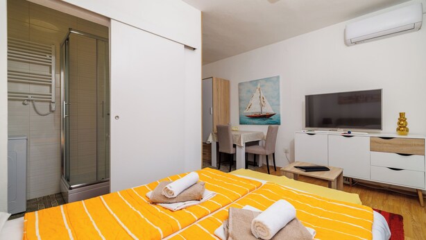 Una habitación de hotel con cama, escritorio, televisor y un cuadro de un velero.
