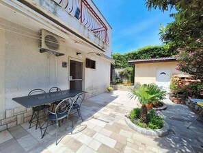 A courtyard with a table and chairs, potted plants, and a building with a balcony.