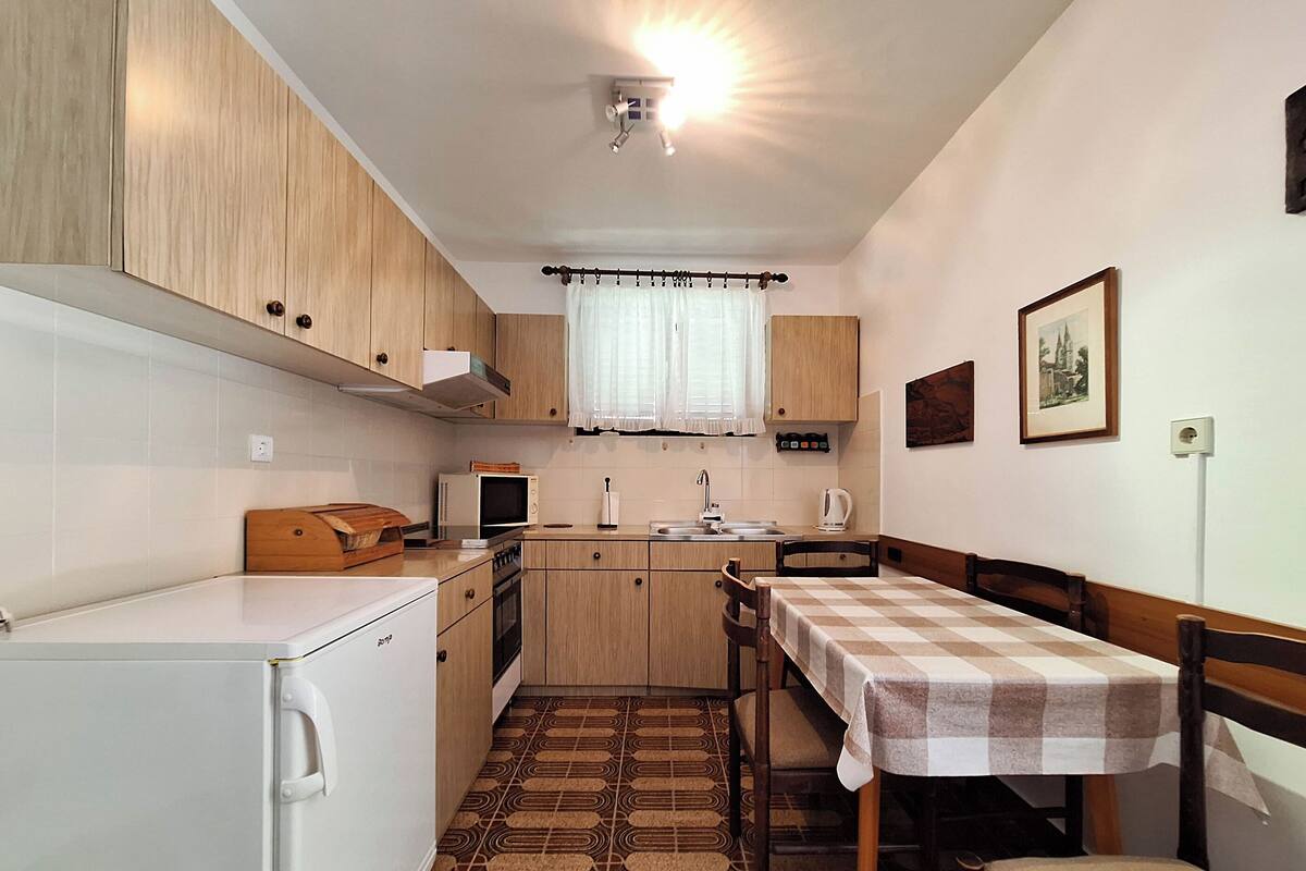 A compact kitchen with a microwave, sink, and a dining table with a checkered tablecloth.