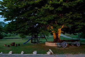 Explore a serene park setting with a playground featuring a swing set, slide, and tree with a bench.