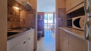 A narrow kitchen with a stove, microwave, and cabinets. - Comfortable studio near slopes, 4 people, Wifi, parking (Le Dévoluy)