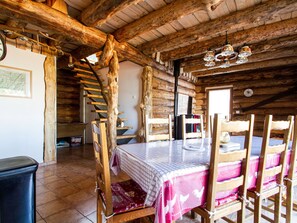 A rustic wooden cabin with a dining table set for four, surrounded by wooden chairs.