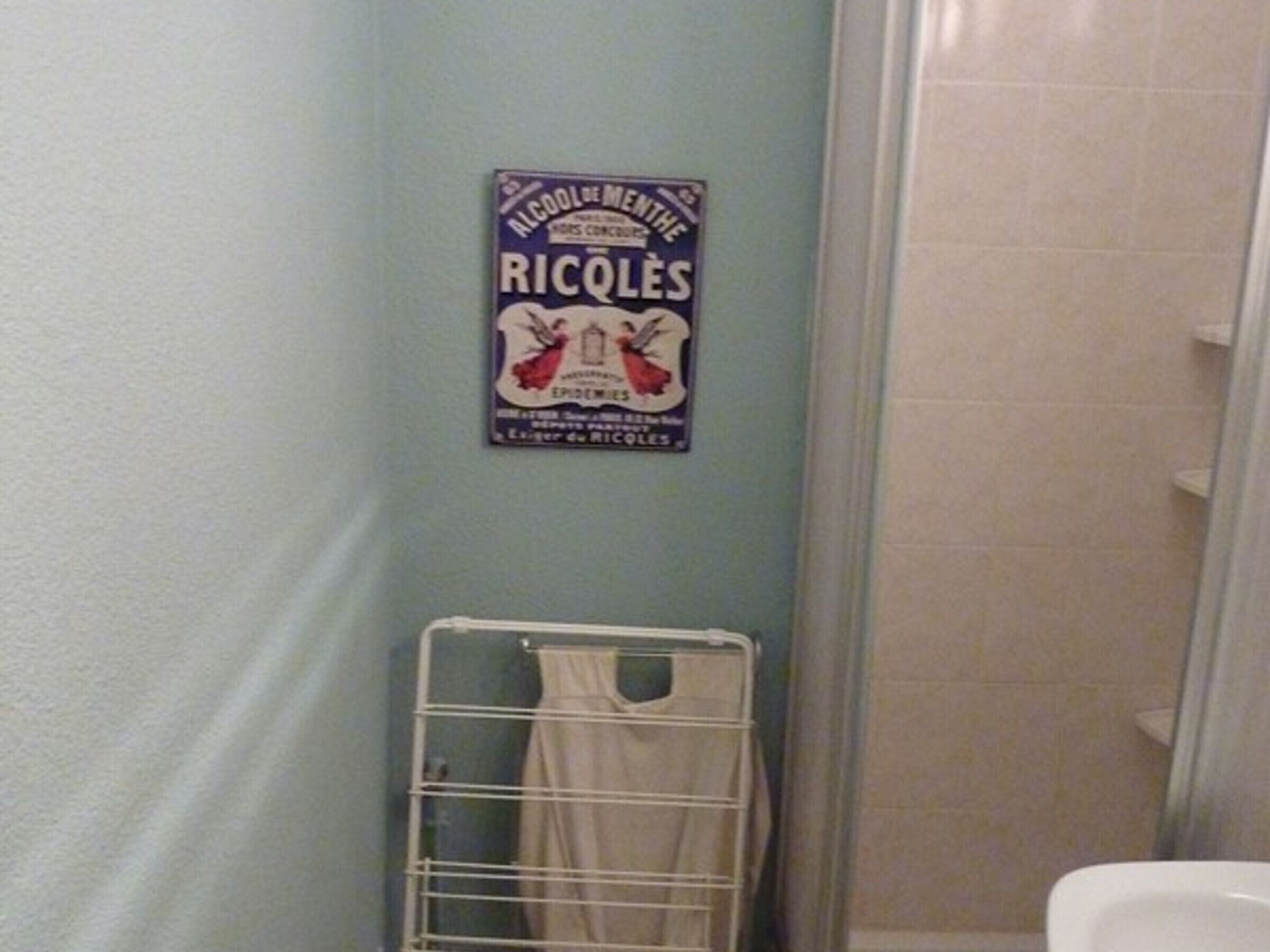 A bathroom with a shower, a towel rack, and a sign on the wall.
