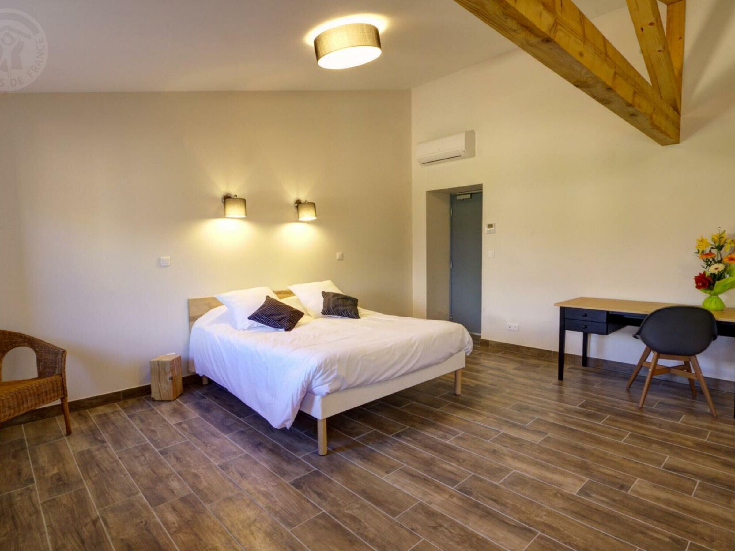 A bedroom with a bed, a desk, and a chair.