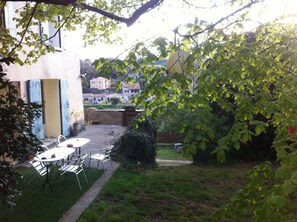 Un patio con una mesa y sillas, un pequeño jardín y vistas a edificios al fondo.