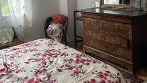 Un dormitorio con cama, cómoda y un espejo grande.