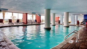 An indoor swimming pool with clear water, surrounded by lounge chairs and a tiled floor. - Heaven on Earth Summa (Myrtle Beach)