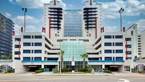 A modern building with a central glass facade, multiple floors, and a symmetrical design. - Heaven on Earth Summa (Myrtle Beach)