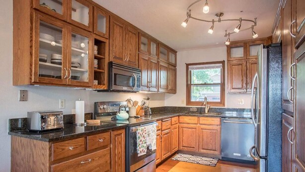 A kitchen with wooden cabinets, a stainless steel refrigerator, a microwave, and a toaster. - Spacious home in the South Hills of Missoula with a great view. (Missoula)