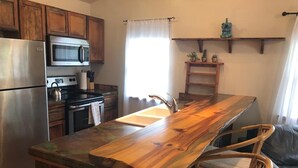 A kitchen with a wooden island, stainless steel appliances, wicker chairs, and a window with curtains. - Cozy condo located in central Missoula on the Milwaukee Path bike trail. (Missoula)