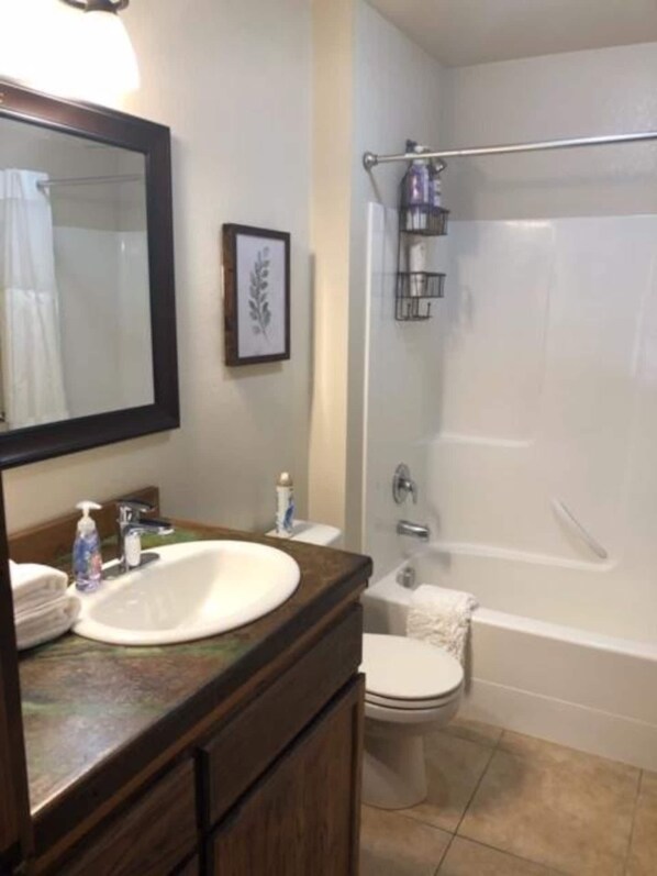 A bathroom with a sink, mirror, toilet, and bathtub. - Cozy condo located in central Missoula on the Milwaukee Path bike trail. (Missoula)