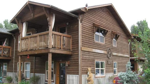 A two-story wooden building with a balcony on the upper floor, a front door, and a small porch area. - Cozy condo located in central Missoula on the Milwaukee Path bike trail. (Missoula)