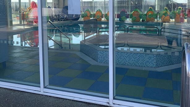 Uima-allasalue, jossa on laatoitettu allasterassi ja lasinen suojaseinä.