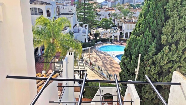 Vista di un resort con piscina, palme e un mix di architettura tradizionale e moderna.