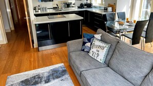 A modern kitchen with black cabinets, a central island, and a dining area with a glass table and black chairs.